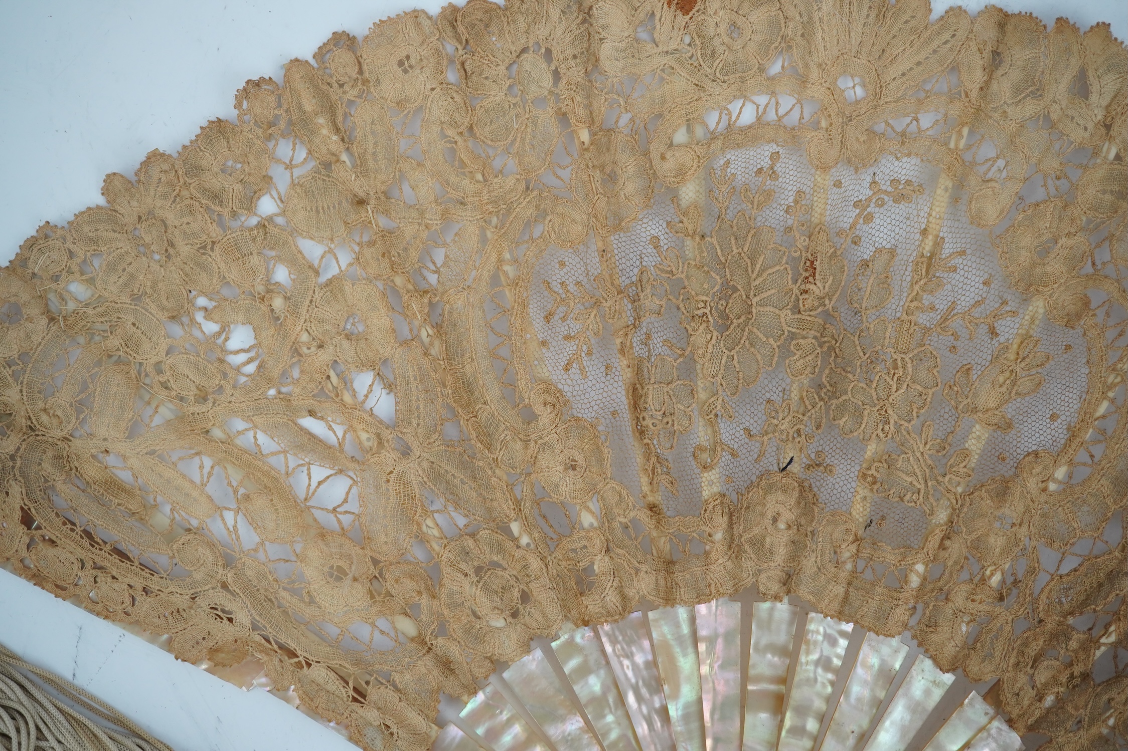 Three novelty fans with a mixed Brussels lace fan and black lace fan, a small language of love in flowers fan, a paper windmill advertising French Café fan, a carved cream Bakelite fan, a black and gilt, lace and sequin